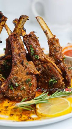 two pieces of lamb chops on a plate with lemon wedges and garnishes