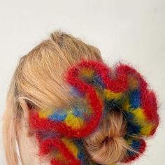 a woman with her hair in a bun is wearing a multicolored knitted scrunchy