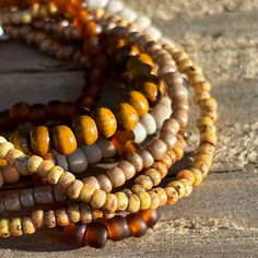 This is a lovely coordinated stack of 6 stretch seed bead and wood bracelets in earthy brown tones. Perfect for dressing up, a casual day out, or no occasion at all! Rearrange the bracelets to get the exact style you like, or add them to some of your existing favorites to customize your accessorizing. Looks fantastic paired with gold. Set includes one each of: deep amber, Picasso matte canary yellow, Picasso matte brown, off-white/stone solid color, metallic khaki, and one wood bead bracelet.  As a handmade item, each set will vary slightly due to randomization of patterns.  Giving as a gift? The 7" size is considered "standard" and fits a lot of teens and adults. Treating yourself? Measure your wrist to choose your desired size. Selecting a set that's a little larger means the stack will Brown Beaded Bracelets For Beach, Brown Beaded Bracelets For Beach With Round Beads, Brown Heishi Beads Jewelry With Tiny Beads, Brown Heishi Beads Bracelet, Handmade Brown Heishi Beads, Brown Beaded Heishi Bracelets, Brown Heishi Beads Bracelet With Colorful Beads, Brown Heishi Beads Bracelets With Colorful Beads, Bohemian Hand-strung Brown Beads