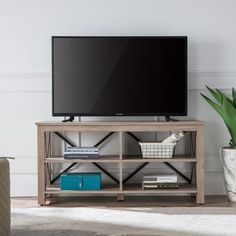 a flat screen tv sitting on top of a wooden shelf next to a chair and potted plant