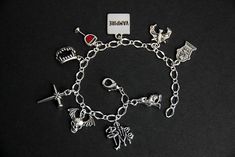 "A collection of silver plated vampire themed charms have been dispersed around a shimmering silver plated bracelet chain in this handmade charm bracelet. This vampire charm bracelet is then completed with a lobster clasp and a 1/2 inch of chain at the end for adjustable sizing. Charms in this bracelet include a gravestone charm, an enameled blood in a glass charm, \"vampire\" word tag charm, howling wolf charm, winged skull charm, vampire bat charm, vampire teeth charm, cross made of stakes cha Vampire Shoes, Handmade Charm Bracelets, Tooth Charm, Winged Skull, Gothic Bracelet, Wife Jewelry, Vampire Teeth, Vampire Bat, Howling Wolf