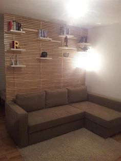 a living room with a sectional couch and shelves on the wall behind it in front of a window