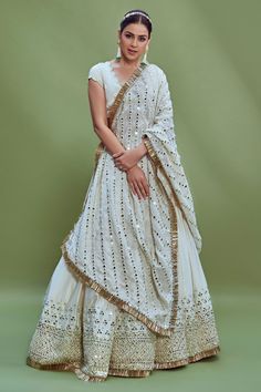 Ivory chanderi lehenga with mirror embroidery on the border and fringe detail at the hem. Comes with blouse and dupatta.
Component: 3
Pattern: Embroidery
Type Of Work: Mirror, Thread and Beads
Neckline: V neck
Sleeve Type: Cap
Fabric: Blouse: Satin Glace, Lehenga: Heavy Chanderi and Dupatta: Linen
Color: White
Other Details: 
Blouse with scalloped border and bead drops
Dupatta with mirror embroidery and fringe border
Tie up at the back
Occasion: Bride - Aza Fashions White Gown With Pallu For Festivals, White Pre-draped Saree With Gota Work For Navratri, White Chinon Reception Sets, White Chandbali Lehenga With Resham Embroidery, White Anarkali Pre-draped Saree With Dupatta, Off White Saree Set With Gota Work, Reception Lehenga In Off White With Sheer Dupatta, Off White Lehenga With Sheer Dupatta For Reception, Off White Pre-draped Saree With Dupatta For Reception