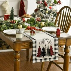 a dining room table decorated for christmas with holiday decorations on the table and trees in the background