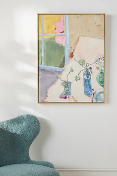 a blue chair sitting in front of a painting on the wall next to a window