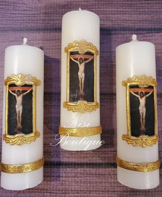 three white candles with gold trim and a crucifix