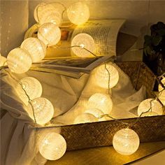 some white lights are hanging on a shelf next to a basket with books in it