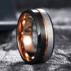 a black and gold wedding band with an orange inlay