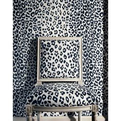 a leopard print wallpaper with a chair in the foreground and an upholstered back