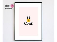 a framed poster with the words be kind in black and yellow on it, against a white wall