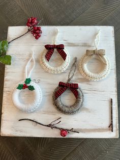 four christmas wreaths are hanging on a wooden board