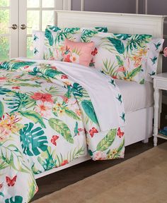 a bed with white sheets and colorful flowers on it