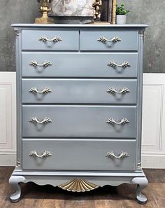 a grey dresser with gold handles and drawers