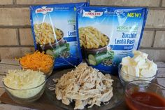 three bags of frozen food sitting on top of a table next to bowls of vegetables