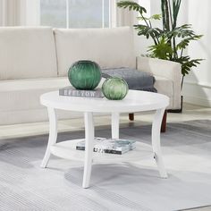 a white coffee table with two green vases sitting on it's top in front of a couch