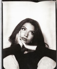 a black and white photo of a woman with her hand on her chin