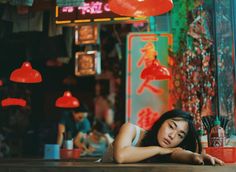 a woman laying on the ground in front of a bar with neon signs above her