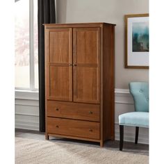 a wooden armoire with two drawers and a blue chair in front of the window