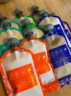 six water bottles with labels on them sitting on a wooden floor next to each other