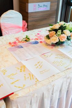 the table is set up with flowers and cards for guests to write their names on