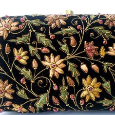 "Beautiful designer luxury black velvet hard case clutch bag, hand embroidered with a rich palette of caramel colored flowers and embellished with ruby gemstones. This will be your go to purse for any wedding! A classic design that never goes out of style. Expertly hand embroidered by third generation zardozi artisans. The word Zardozi means \"gold thread\". It is an elaborate and intricate multidimensional embroidery using metallic threads and genuine precious and semi precious gemstones. A cen Bride Purse, Velvet Clutch Bag, Embellished Purses, Flowers Luxury, Thread Necklace, Floral Handbags, Velvet Clutch, Types Of Gifts, Wedding Purse