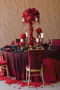 the table is set with red flowers and candles