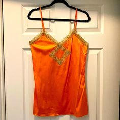 Brand New With Tag! Orange Silk Camisole With Gold Lace Trim! -88% Silk -12% Spandex -Perfect Condition! Never Worn! -Adjustable Straps -Length As Shown 31.5” (Can Go Longer Or Shorter) -17” Bust Orange Spaghetti Strap Camisole For Summer, Orange Spaghetti Straps Camisole For Summer, Orange Stretch V-neck Top, Stretch Orange V-neck Top, Orange Stretch Tank Top For Party, Summer Orange Cami Tank Top, Stretch Orange Tank Top For Party, Orange Cami Tank Top For Summer, Orange Sleeveless Camisole For Spring