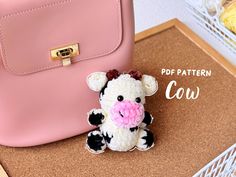 a stuffed cow sitting next to a pink purse on top of a cork board with the caption pop pattern cow