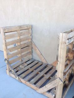 a bed made out of wooden pallets sitting on top of a cement floor next to a wall