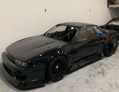 two black cars parked in a garage next to each other