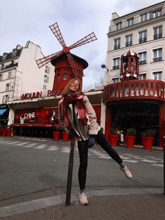 a woman posing for a photo in front of a building with a windmill on top