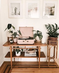 a record player sitting on top of a wooden table next to potted plants and pictures