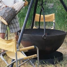 a man standing next to a large metal bowl on top of a grass covered field