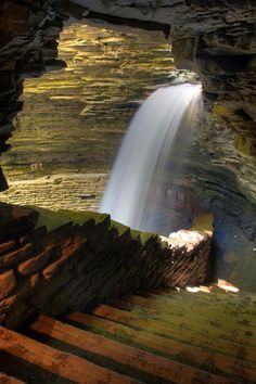 a waterfall is seen from the inside of a cave with steps leading up to it