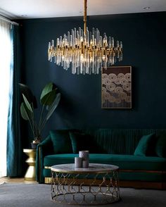 a living room filled with green furniture and a chandelier hanging from the ceiling