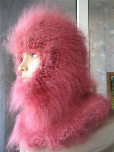 a mannequin's head is covered in pink fuzzy fur and sits next to a window