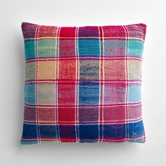 a colorful plaid pillow on a white wall