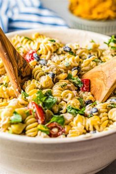 a bowl filled with pasta salad and a wooden spoon in the bowl next to it