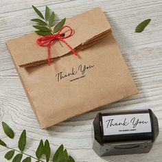 a wax stamper next to a brown envelope with a red bow on it and some green leaves