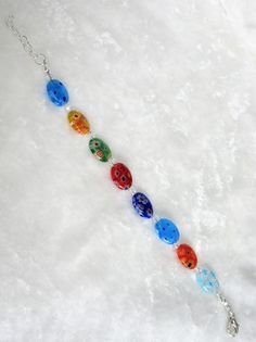 a necklace with seven colorful beads hanging from it's side on a white surface