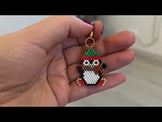 a hand holding a keychain with an image of a penguin wearing a santa hat