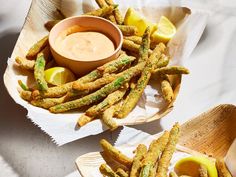 two baskets filled with fried asparagus and dipping sauce