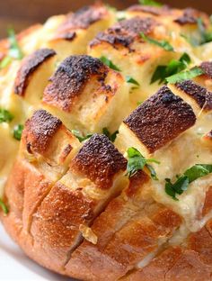 a bread dish with cheese and herbs on it sitting on a white plate, ready to be eaten