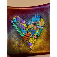 a heart made out of different colored items on a brown and purple pillow with gold foil