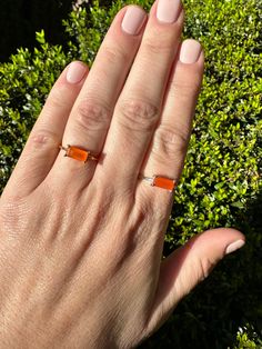 A bright orange burst of color and energy, this natural Carnelian baguette is simply set in a prong setting in Sterling Silver or Gold over Sterling to allow the beauty and intensity of the gem to truly shine. Known as a stone of courage and endurance, it symbolises bold energy, positivity, and empowerment. Orange Rectangular Jewelry As Gift, Modern Orange Gemstone Rings, Polished Carnelian Orange Jewelry, Orange Polished Carnelian Jewelry, Modern Orange Rings As Gifts, Modern Orange Rings For Gifts, Modern Orange Rings For Gift, Orange Carnelian Ring Jewelry, Solitaire Rings