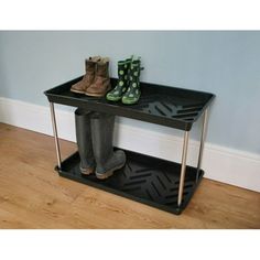 two pairs of boots sitting on top of a black shelf next to a wooden floor