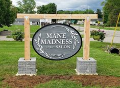 the sign for manedness salon is in front of some trees and grass with flowers