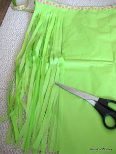 a pair of scissors sitting on top of a green piece of paper next to some streamers