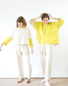 two women standing next to each other with their hands on their head