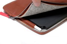 a person holding an electronic device in their hand with a zippered pouch on it